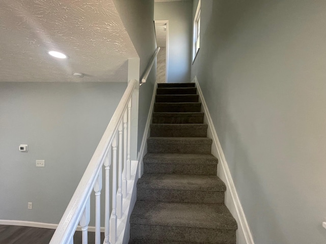 stairs featuring a textured ceiling and hardwood / wood-style flooring