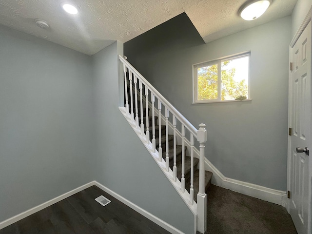 stairway featuring hardwood / wood-style floors and a textured ceiling