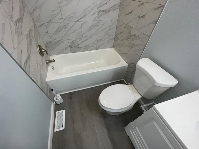 bathroom featuring hardwood / wood-style floors, tiled shower / bath combo, and toilet