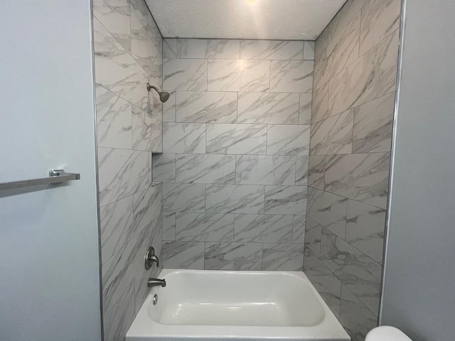 bathroom featuring toilet and tiled shower / bath