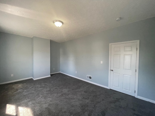 spare room with dark colored carpet and a textured ceiling