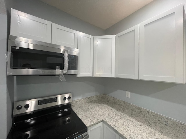 kitchen with white cabinets, light stone countertops, and appliances with stainless steel finishes