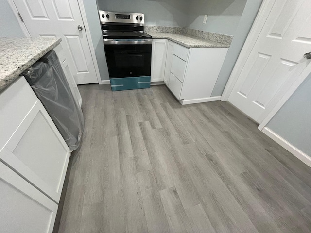 kitchen with electric stove, white cabinets, and light hardwood / wood-style floors