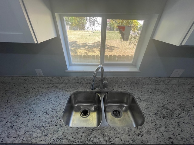 details with white cabinetry, tasteful backsplash, light stone countertops, and sink