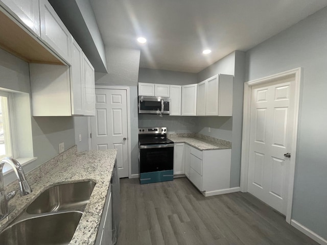 kitchen featuring white cabinetry, sink, light stone counters, dark hardwood / wood-style flooring, and appliances with stainless steel finishes