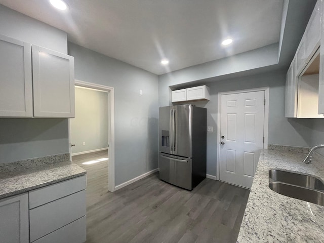 kitchen featuring light stone countertops, sink, stainless steel fridge with ice dispenser, dark hardwood / wood-style floors, and white cabinetry