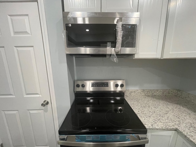 kitchen with white cabinets, appliances with stainless steel finishes, and light stone countertops