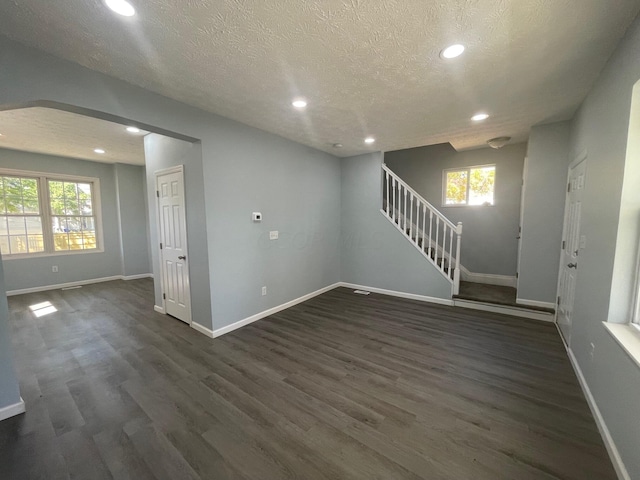 unfurnished room featuring a textured ceiling, plenty of natural light, and dark wood-type flooring