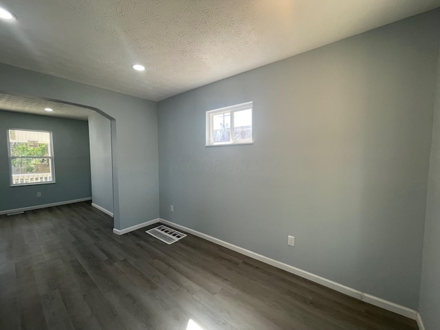 empty room with dark wood-type flooring and a textured ceiling