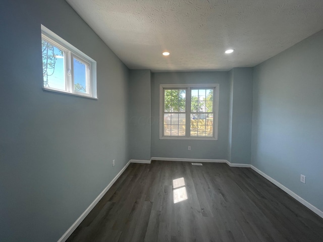 spare room featuring dark hardwood / wood-style floors and a textured ceiling