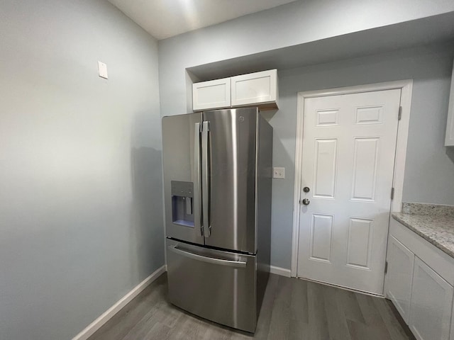 kitchen featuring white cabinets, stainless steel refrigerator with ice dispenser, dark hardwood / wood-style flooring, and light stone counters