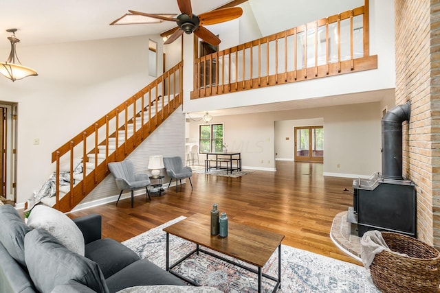 living room featuring wood-type flooring, high vaulted ceiling, a wood stove, and a wealth of natural light