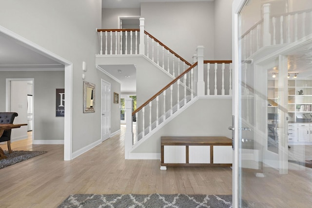 foyer featuring light hardwood / wood-style flooring, a high ceiling, and ornamental molding