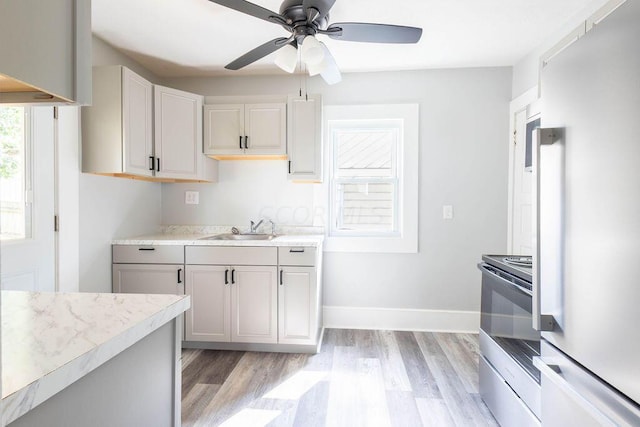 kitchen with stainless steel electric stove, sink, light hardwood / wood-style floors, and fridge