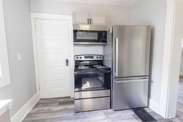 kitchen featuring white cabinets, appliances with stainless steel finishes, and light wood-type flooring