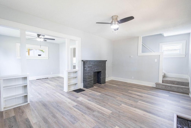 unfurnished living room with ceiling fan, plenty of natural light, light hardwood / wood-style floors, and a brick fireplace