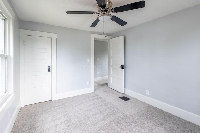 unfurnished bedroom featuring ceiling fan, light carpet, and multiple windows