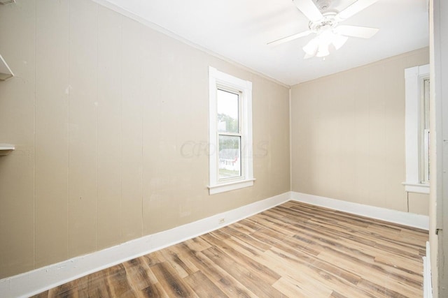 empty room with light hardwood / wood-style floors, ceiling fan, ornamental molding, and wood walls