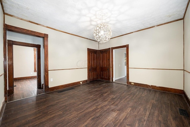 spare room with a textured ceiling, crown molding, and dark hardwood / wood-style floors