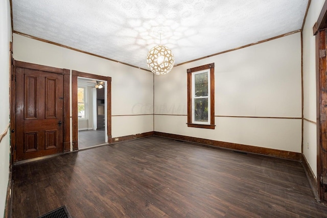 spare room featuring a textured ceiling, dark hardwood / wood-style floors, and crown molding