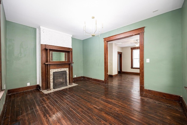 unfurnished living room featuring dark hardwood / wood-style floors, a fireplace, and ceiling fan with notable chandelier