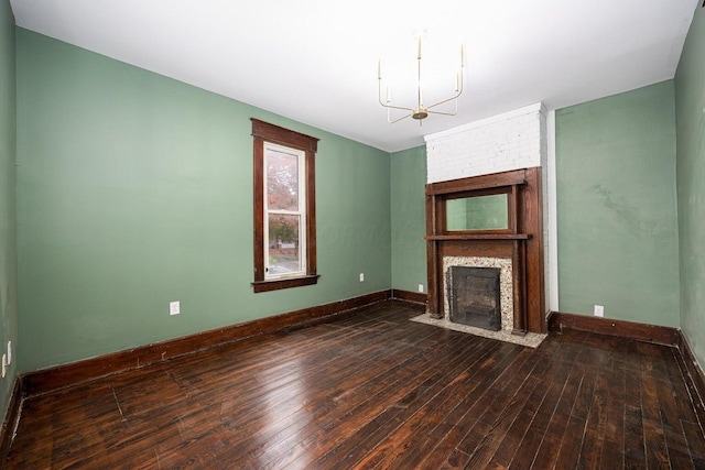 unfurnished living room featuring dark hardwood / wood-style flooring, a fireplace, and an inviting chandelier