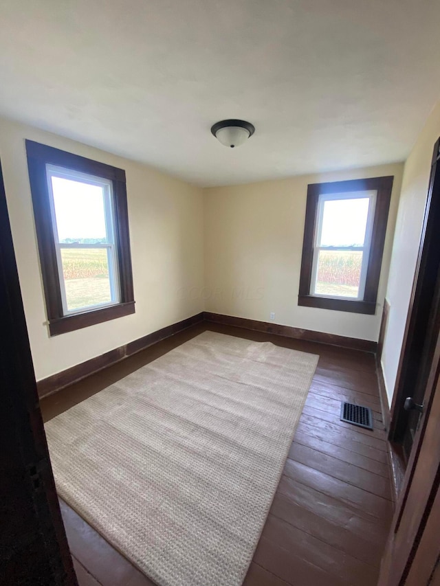 empty room with a wealth of natural light and dark wood-type flooring