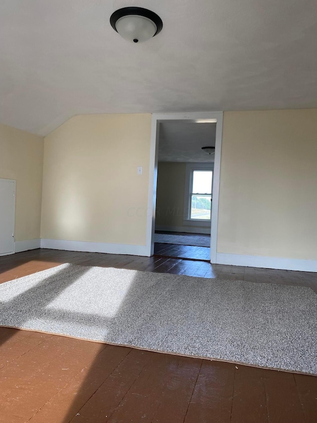 spare room with hardwood / wood-style floors and vaulted ceiling