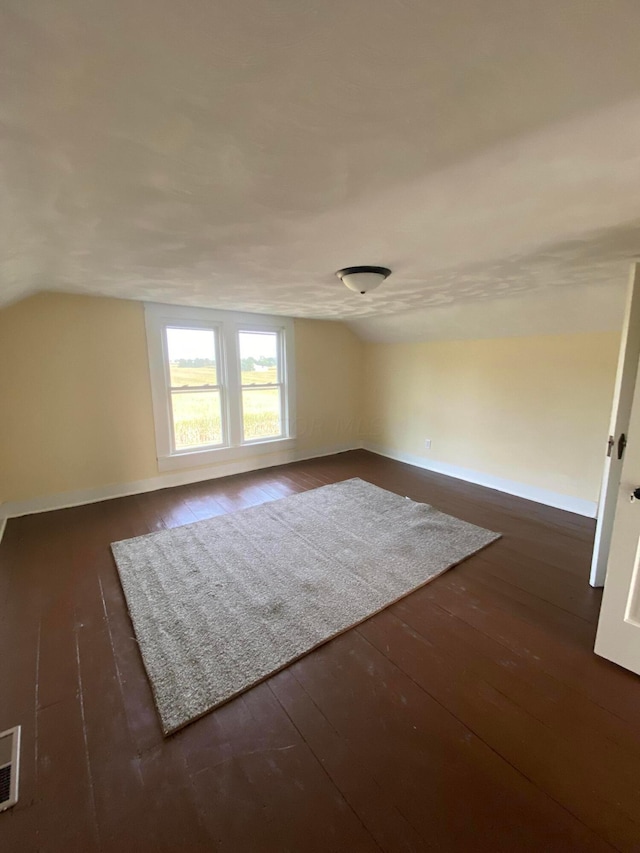 additional living space featuring lofted ceiling and dark wood-type flooring