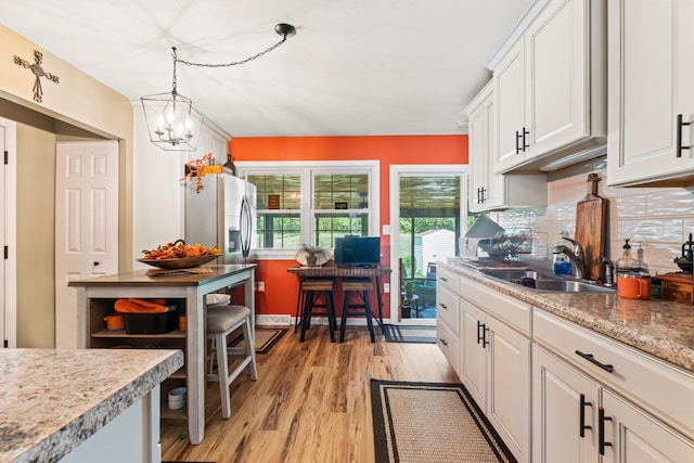 kitchen featuring white cabinetry, sink, a chandelier, light hardwood / wood-style floors, and decorative light fixtures