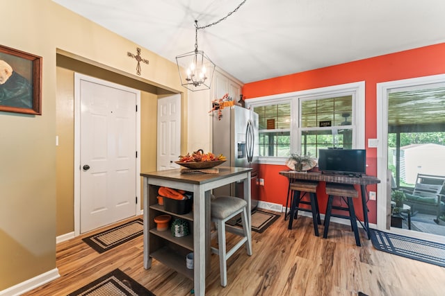 kitchen with hardwood / wood-style floors, stainless steel refrigerator with ice dispenser, hanging light fixtures, and an inviting chandelier