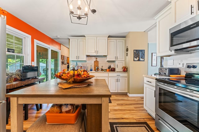 kitchen with hanging light fixtures, light hardwood / wood-style flooring, tasteful backsplash, stainless steel appliances, and a chandelier