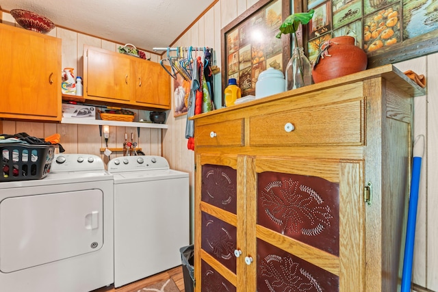 laundry room with wooden walls, hardwood / wood-style flooring, cabinets, and washing machine and dryer