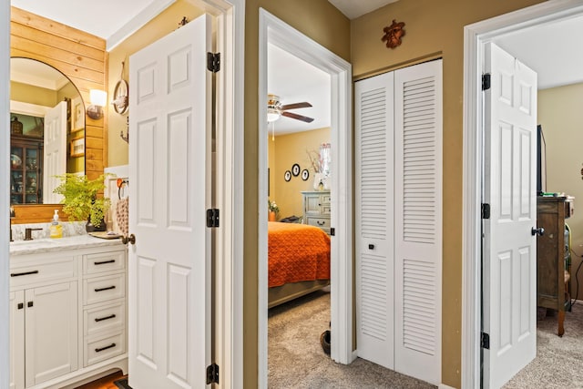 interior space featuring wooden walls, ceiling fan, and vanity