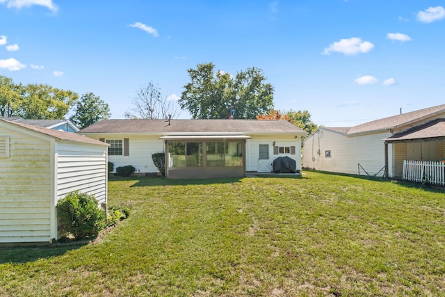 rear view of house featuring a lawn and a sunroom