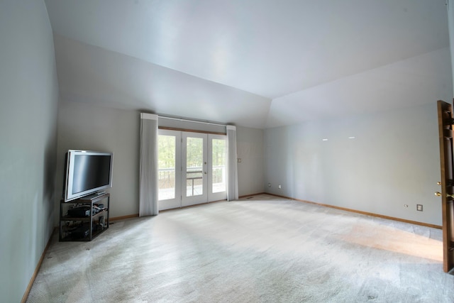 unfurnished living room featuring lofted ceiling, light carpet, and french doors