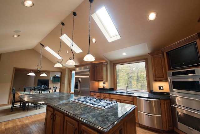 kitchen featuring hardwood / wood-style floors, a center island, sink, vaulted ceiling with skylight, and appliances with stainless steel finishes