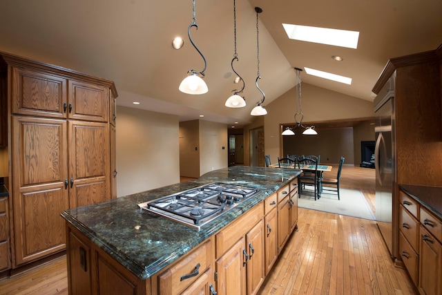 kitchen with hanging light fixtures, light hardwood / wood-style flooring, lofted ceiling with skylight, a kitchen island, and appliances with stainless steel finishes