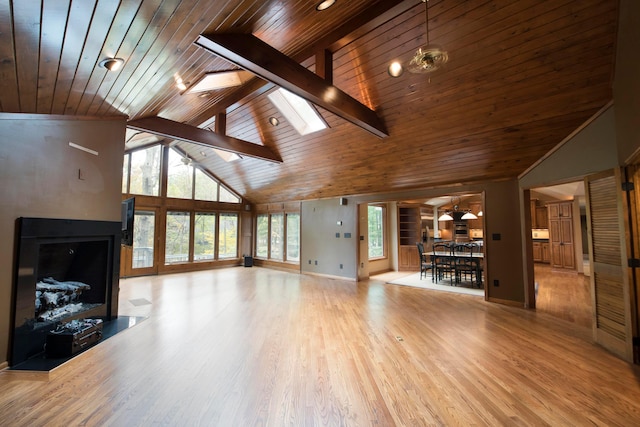 unfurnished living room with beamed ceiling, wooden ceiling, a wealth of natural light, and a skylight