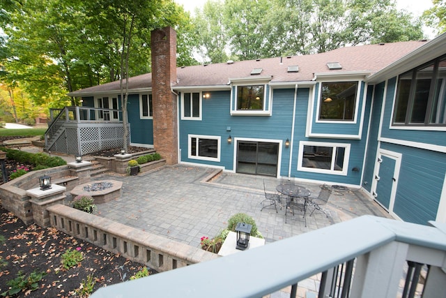 back of property featuring a fire pit, a deck, and a patio