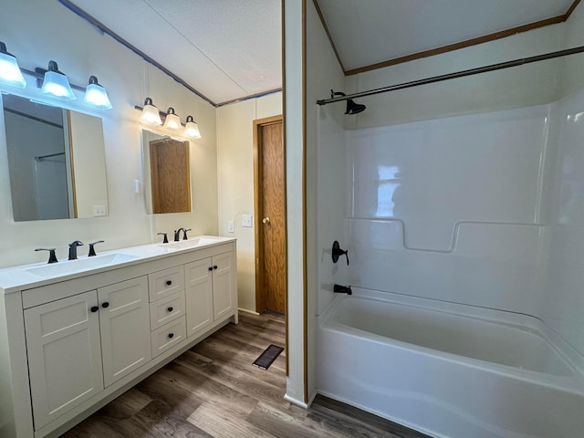 bathroom featuring shower / bathing tub combination, crown molding, wood-type flooring, a textured ceiling, and vanity