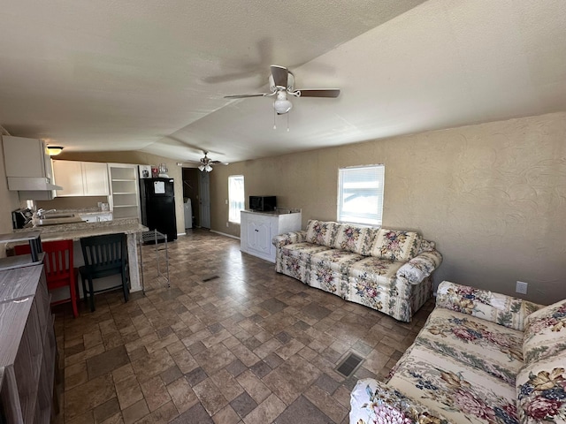 living room featuring ceiling fan, lofted ceiling, and sink