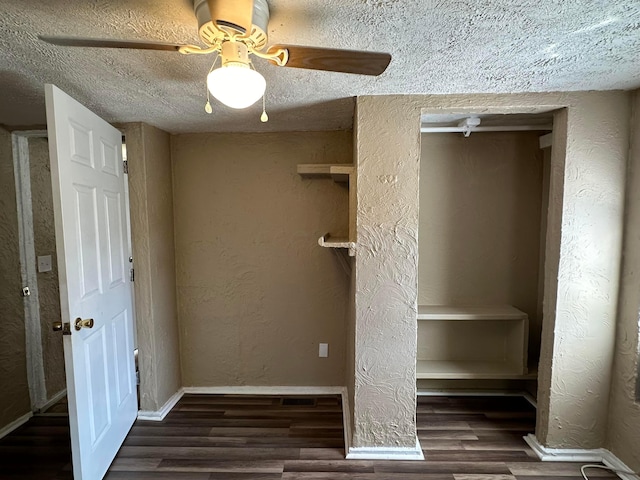 unfurnished bedroom with a textured ceiling, ceiling fan, dark wood-type flooring, and a closet