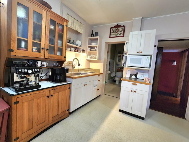 kitchen with white cabinetry, sink, and white microwave