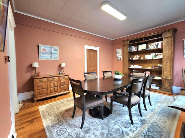 dining room with light wood-type flooring and ornamental molding