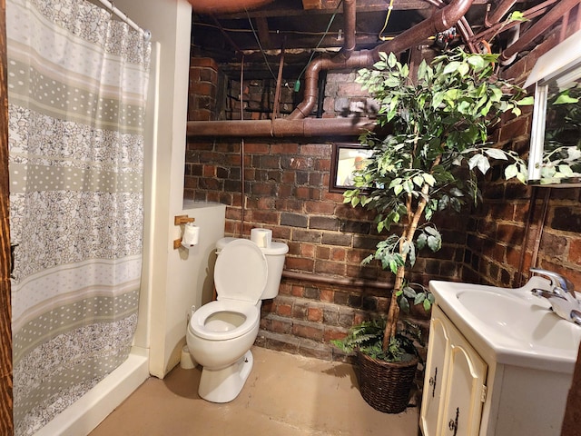 bathroom with vanity, toilet, walk in shower, and brick wall