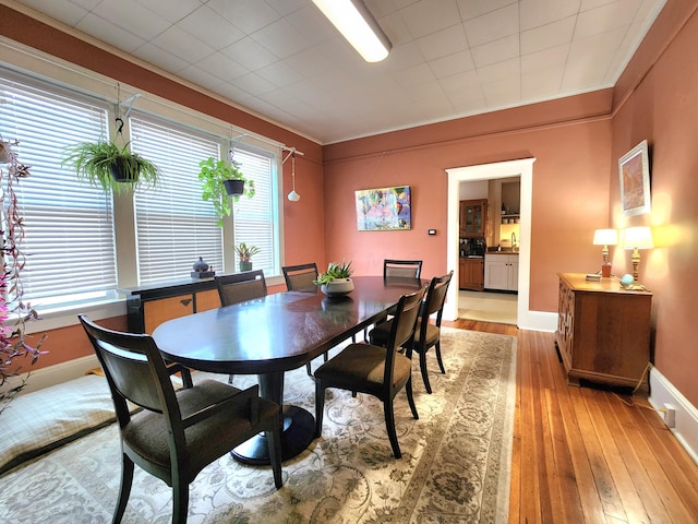 dining space featuring ornamental molding, sink, and light hardwood / wood-style flooring