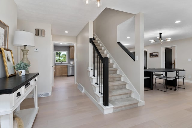 stairs featuring hardwood / wood-style flooring and a notable chandelier