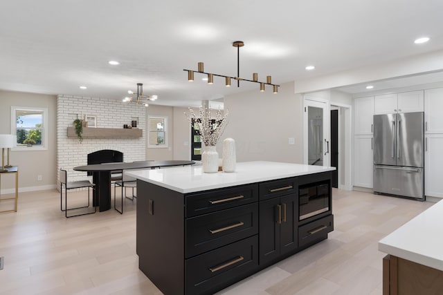 kitchen featuring stainless steel fridge, black microwave, pendant lighting, white cabinets, and a center island