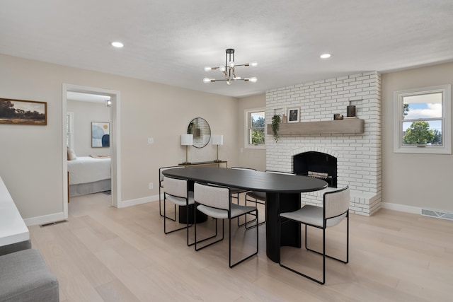 dining space featuring a notable chandelier, light wood-type flooring, and a fireplace